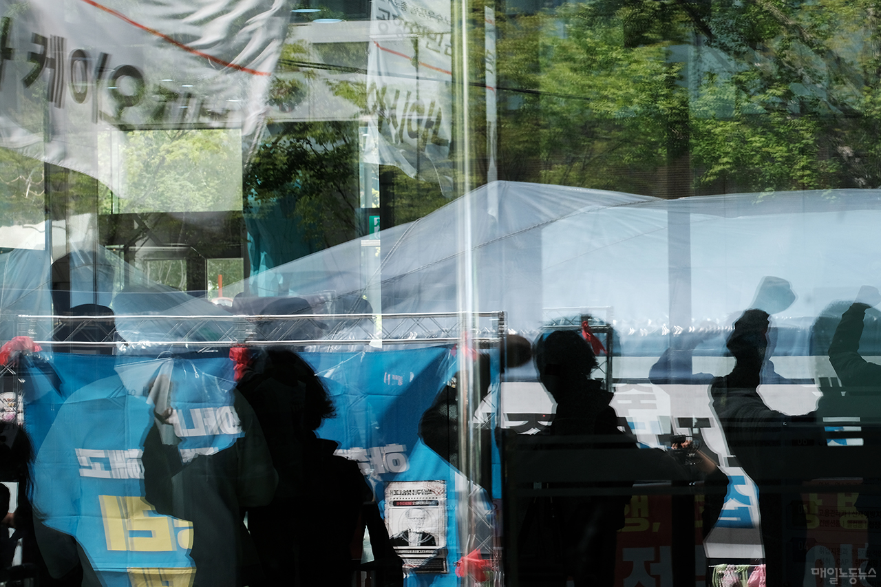 ▲ 4월 말 정년을 앞둔 김정남 아시아나케이오 해고 노동자가 13일 서울지방고용노동청 앞 농성천막 입구에서 정년 전 복직 이행을 촉구하는 노조의 기자회견을 바라보고 있다. <정기훈 기자>