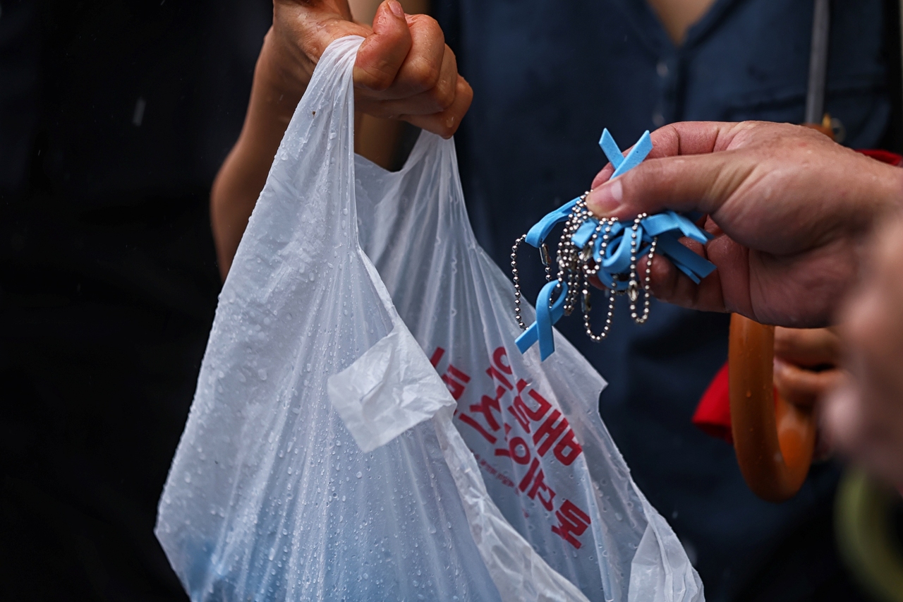 ▲ 시민문화제에 참여한 시민들이 아리셀 참사 기억과 추모를 상징하는 하늘색 리본을 나누고 있다. <윤성희 기자>